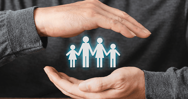 Plano detalle de las manos de una persona con un gráfico que representa una familia en el medio