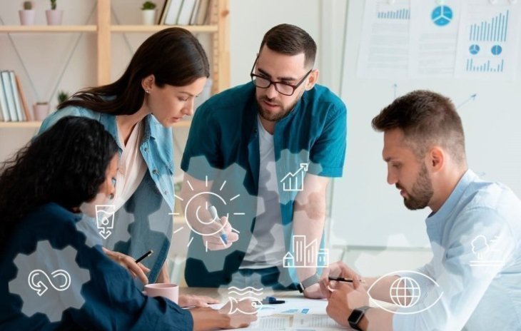 Cuatro personas trabajando en equipo sobre documentos, con íconos digitales superpuestos que representan análisis y planificación.