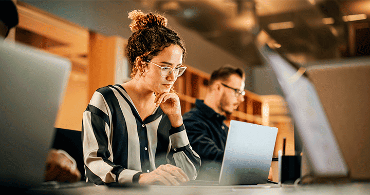 Plano medio de una mujer sentada en el escritorio trabajando en su computador