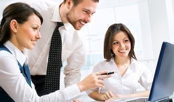 Hombre y dos mujeres en escritorio manipulando un computador